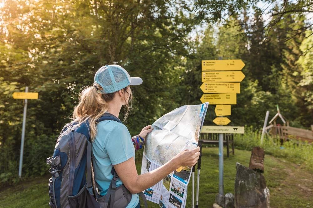 Hiker checking trail information at a trailhead before starting a hike